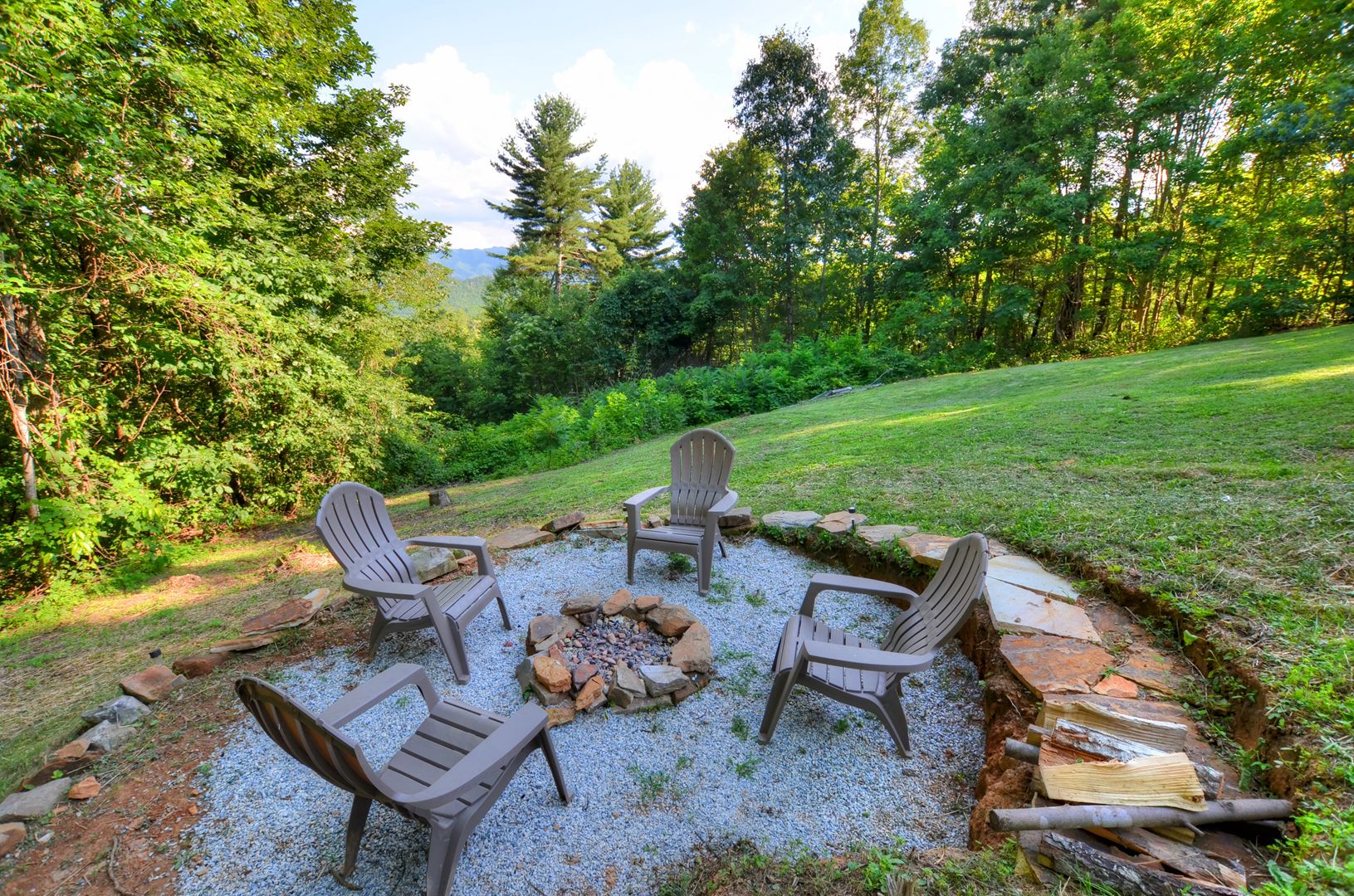Un foyer entouré de fauteuils Adirondack, dans un jardin.