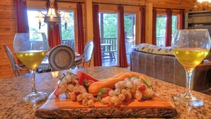A wooden cabin interior with a dining table set for two, featuring a fruit platter and wine glasses.