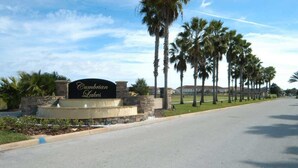 A sign for 'Cumberland Lakes' with a stone wall and palm trees in the background. - Stunning Waterview Pool Home: Gated, 4BR, Outdoor Spa, Games Room, Free WiFi! (Kissimmee)