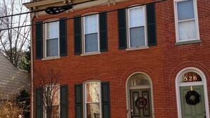 A two-story red brick building with green shutters, a green door, and a number 526 sign. - Lancaster City home with fenced yard and off street parking, walk to downtown (Lancaster)