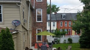 A backyard with a patio area, outdoor furniture, and a grill. - Lancaster City home with fenced yard and off street parking, walk to downtown (Lancaster)
