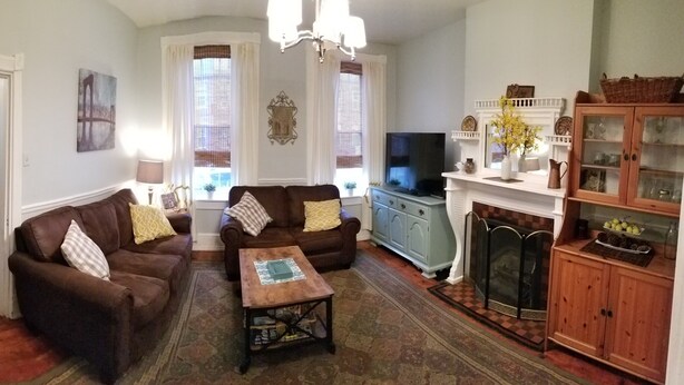 A living room with two brown sofas, a wooden coffee table, a television, a fireplace, and a cabinet with glass doors. - Lancaster City home with fenced yard and off street parking, walk to downtown (Lancaster)