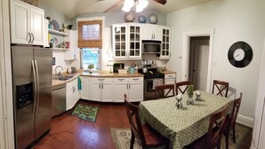 A compact kitchen with white cabinets, a refrigerator, a dining table with chairs, and a clock on the wall. - Lancaster City home with fenced yard and off street parking, walk to downtown (Lancaster)