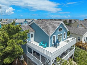 A two-story house with a balcony, a covered deck, and a view of the ocean.