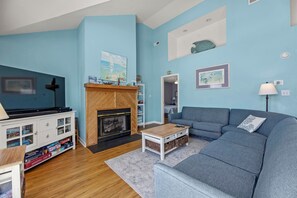 A living room with a fireplace, a sofa, a coffee table, and a TV stand.