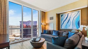 A modern living room with a large window, a sofa, a coffee table, and a painting.