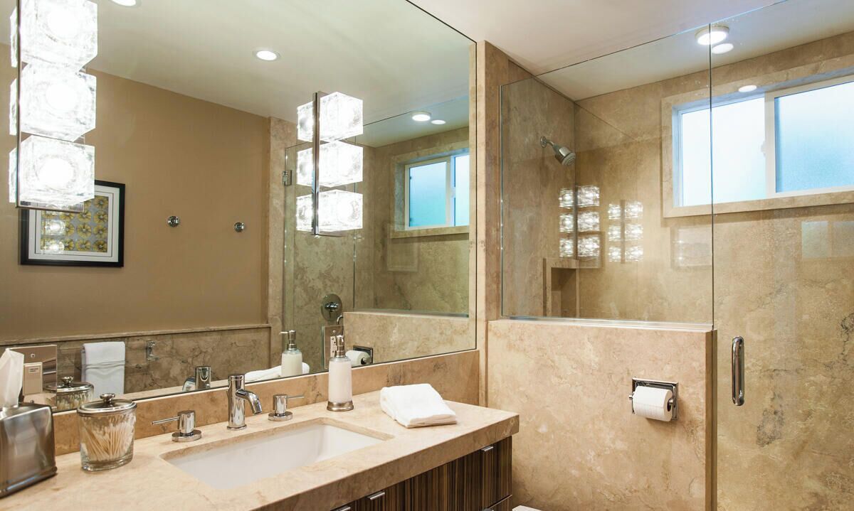 Une salle de bain moderne avec un grand miroir, un lavabo, des toilettes et une douche.
