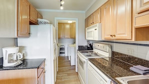 A kitchen with wooden cabinets, a refrigerator, a coffee maker, a stove, and a microwave.