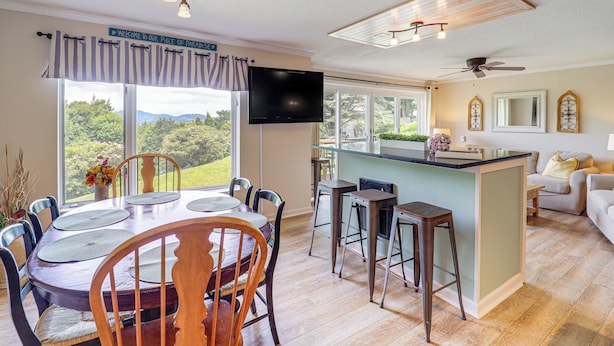 A spacious kitchen with a dining area, large windows, and a view of the outdoors.