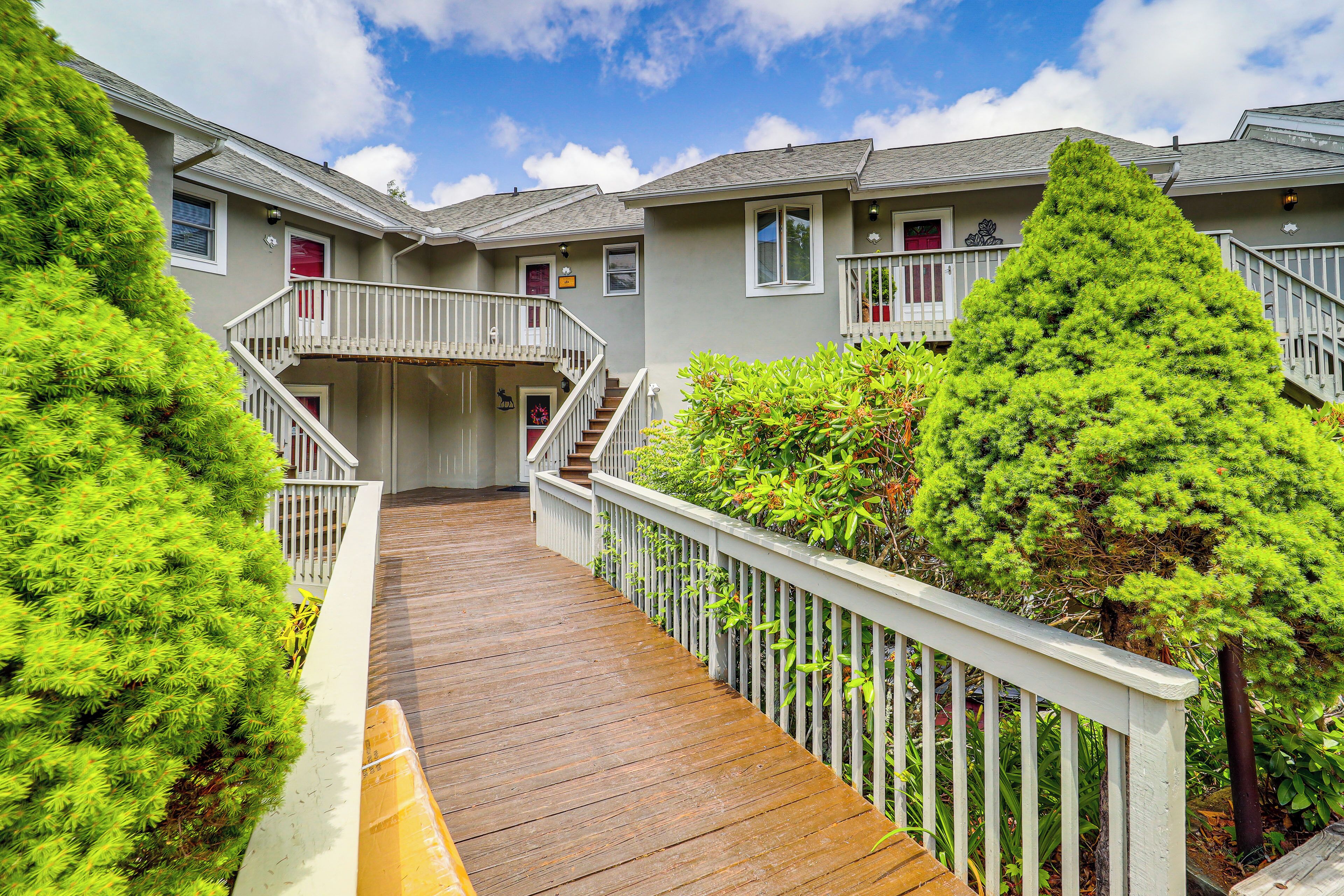 A wooden deck leading to a building with multiple balconies and a staircase.