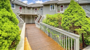 A wooden deck leading to a building with multiple balconies and a staircase.