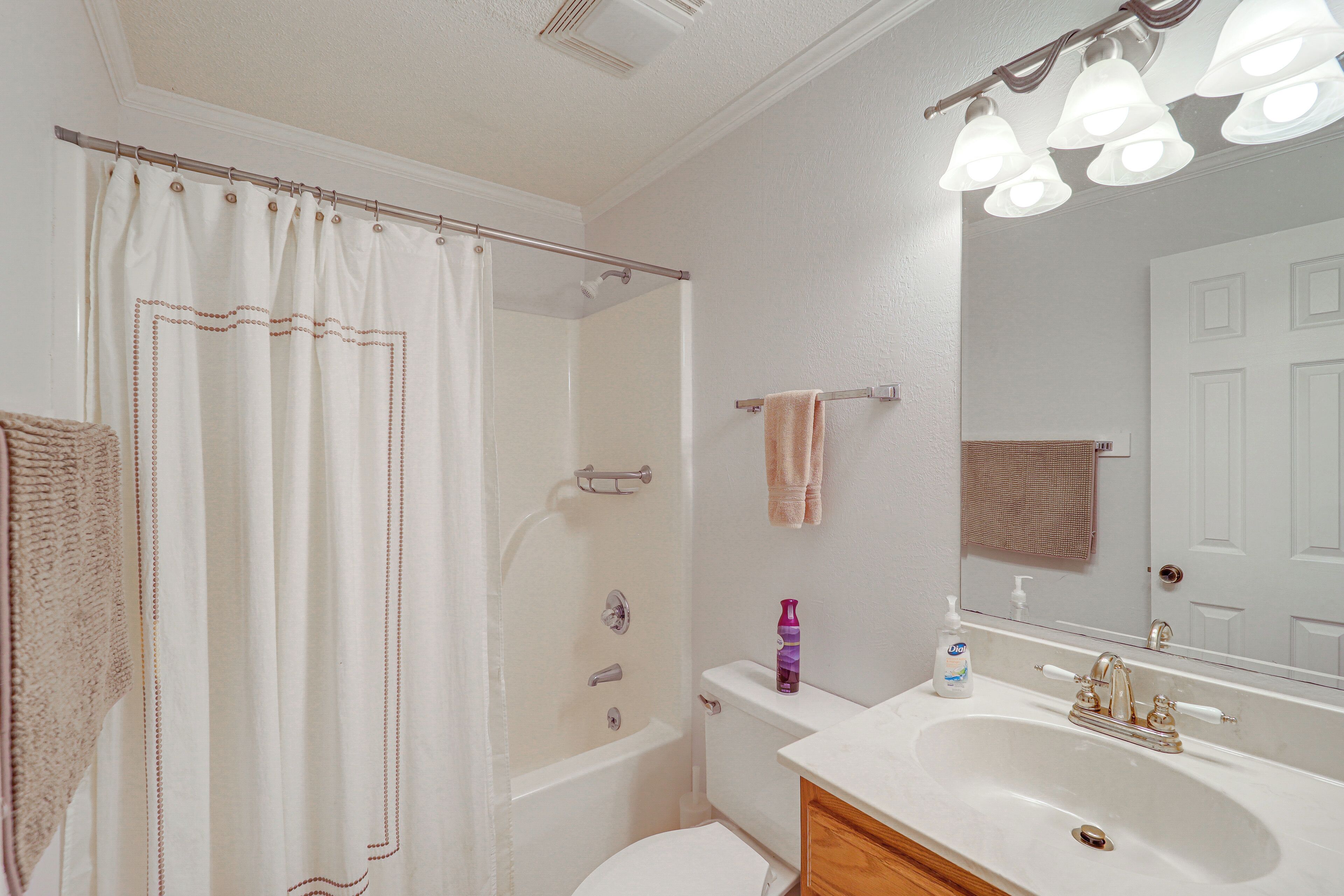 A bathroom with a shower, toilet, sink, and a mirror.