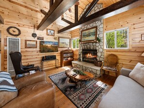 Ein gemütliches Blockhaus-Interieur mit Kamin, Holzwänden und einer komfortablen Sitzecke.