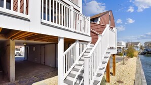 A waterfront property with a covered garage, a staircase leading to a deck, and a view of the water.