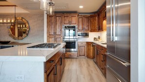 A modern kitchen with wooden cabinets, stainless steel appliances, and a marble countertop.