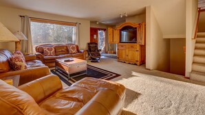 A spacious living room with leather sofas, a coffee table, and a television in a wooden cabinet. - Spacious Home: Hot Tub, Serene Forest (Breckenridge)