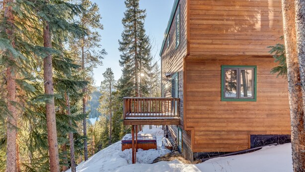 A wooden cabin with a balcony, surrounded by tall pine trees and snow-covered ground. - Spacious Home: Hot Tub, Serene Forest (Breckenridge)