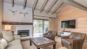 A living room with a fireplace, leather sofa, and a TV.
