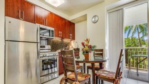 A kitchen with a refrigerator, oven, microwave, and a dining table with chairs.