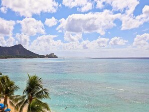 A beach with clear turquoise water, palm trees, and a mountain in the background. - 1 Bedroom Condo w/Park Views - Waikīkī Shore 212 (HONOLULU)