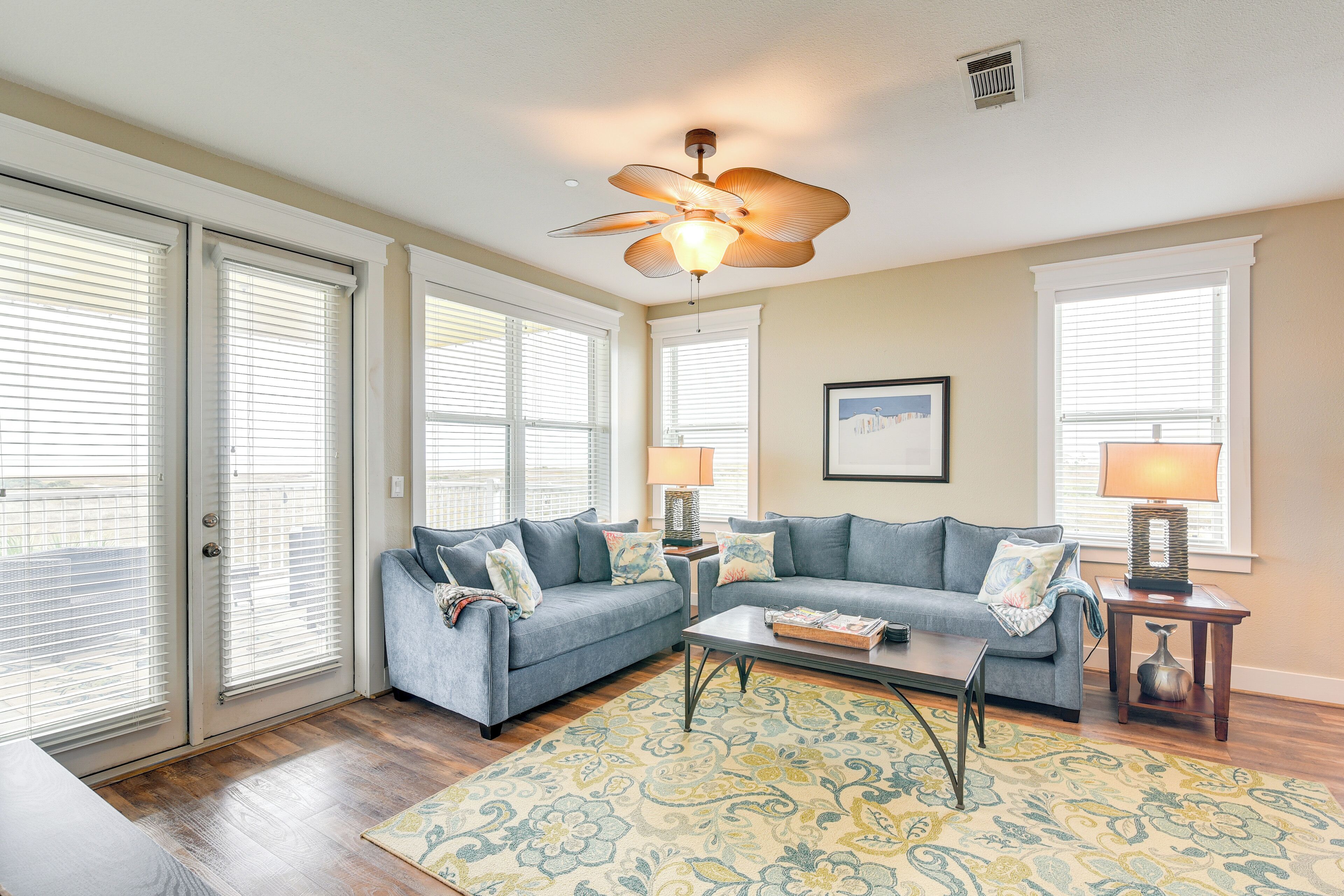 A living room with a ceiling fan, two sofas, a coffee table, and a patterned rug.