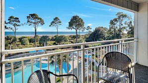 Varanda com vista para uma piscina e praia.