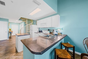 A kitchen with a central island, white cabinets, and a spiral staircase.