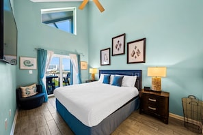 A bedroom with a bed, a nightstand, a chair, a window, and framed pictures on the wall.