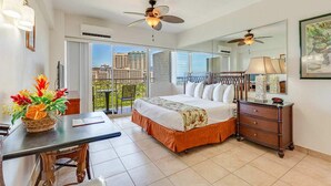 Une chambre d’hôtel comprenant un lit, un bureau, une commode, un miroir et un balcon avec vue sur la ville.