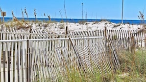Une plage avec une clôture en bois et un mât de drapeau.