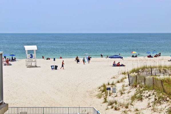 A beach with a lifeguard tower, umbrellas, and people enjoying the sand and water.