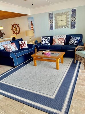 Un salon avec un canapé bleu, une table basse en bois et des coussins décoratifs.