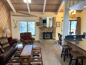 Relax in this inviting living room with a stone fireplace, comfortable sofa, and dining area.