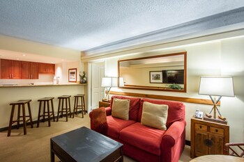 A hotel room with a kitchenette, a coffee maker, a lamp, and framed pictures on the wall. at The Equus