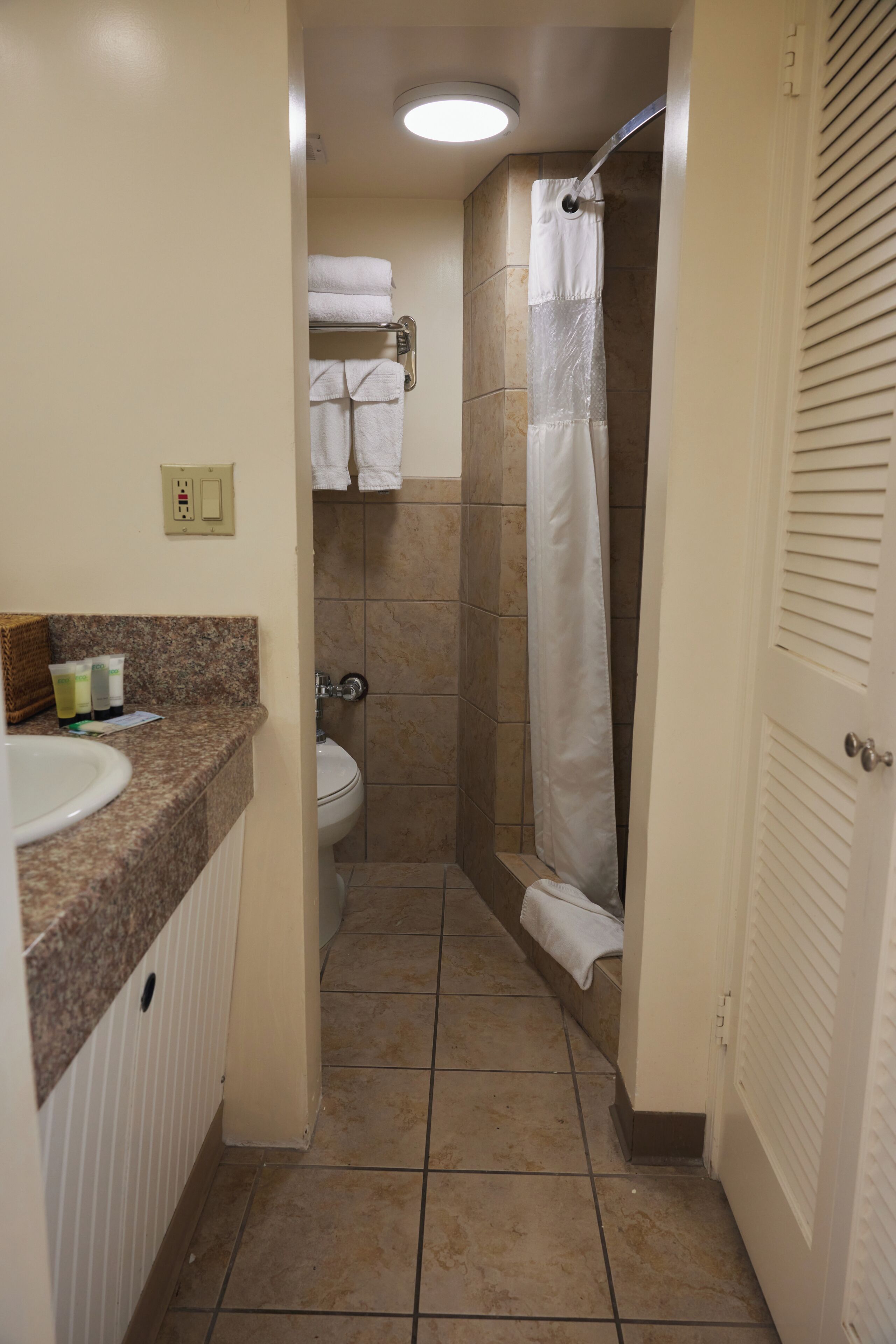 A bathroom with a sink, toilet, shower, and towel rack.