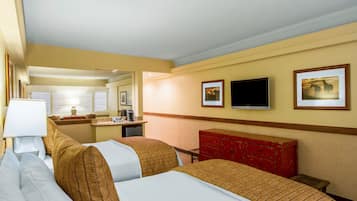 Habitación de hotel con dos camas, un escritorio, un espejo y un televisor.