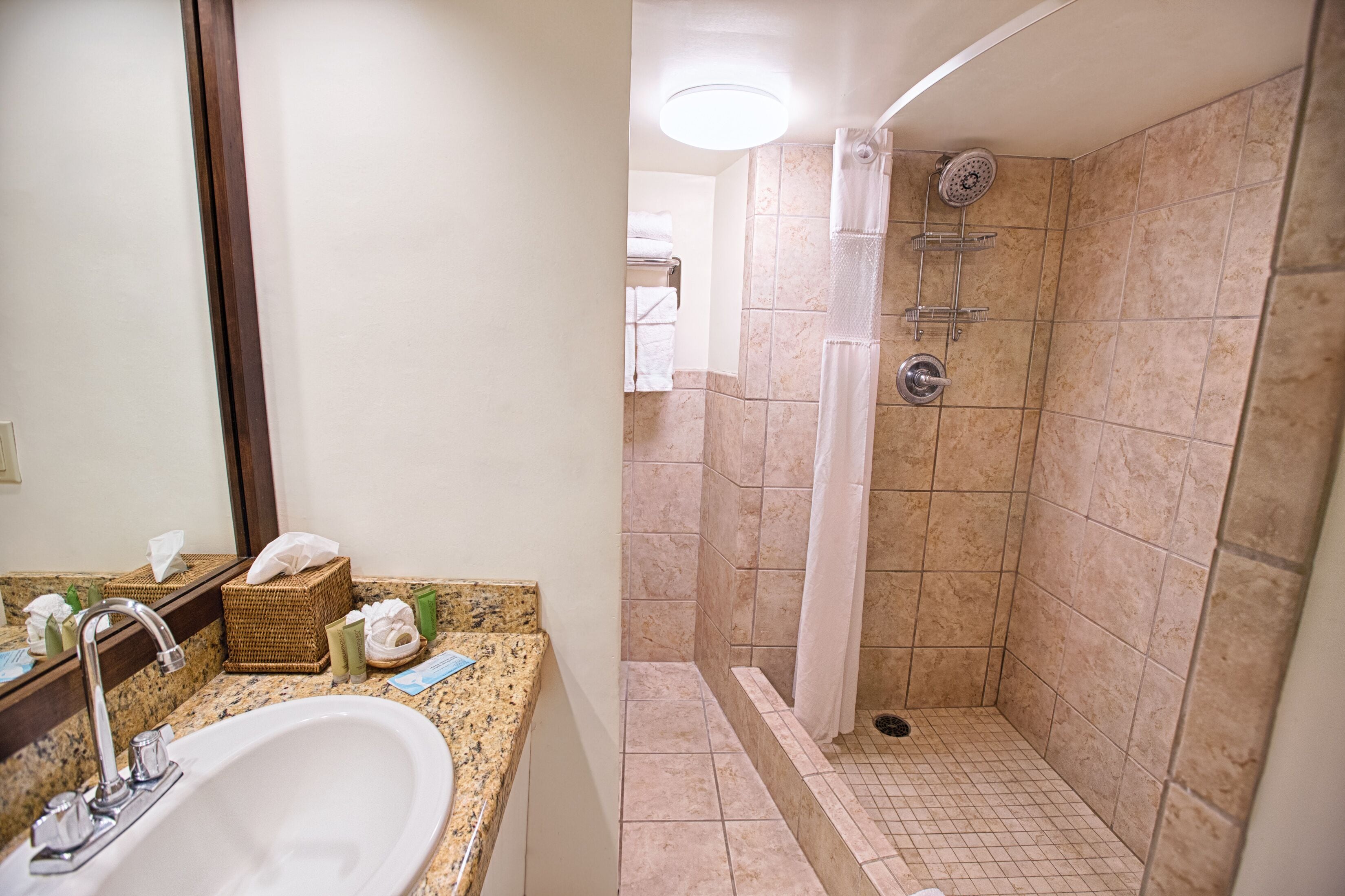 Un baño con lavamanos, espejo y ducha.