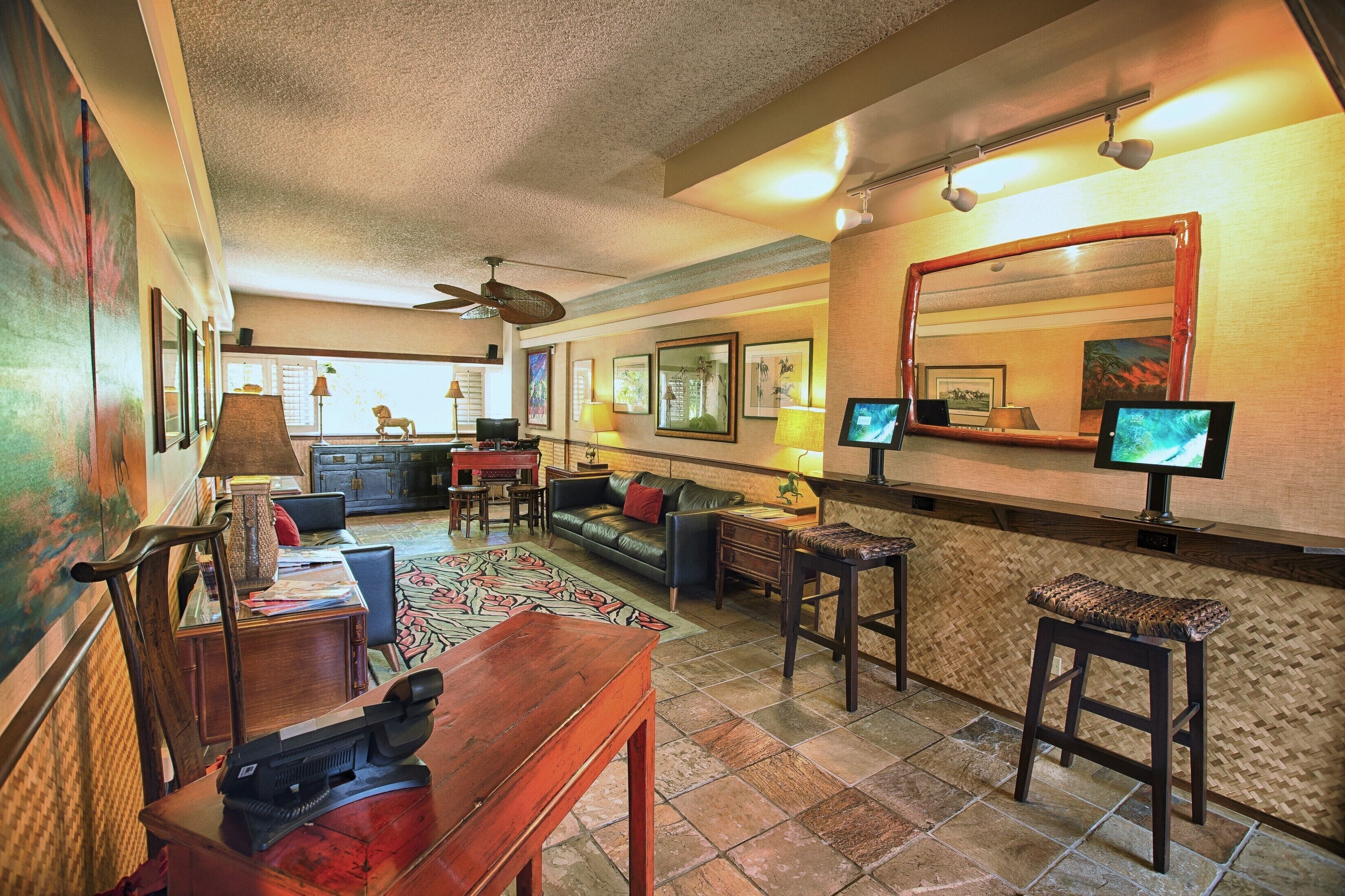 Amplia sala de estar con un sofá grande, una mesa de centro y un televisor. Cuenta con una zona de bar con taburetes y un espejo sobre la barra.