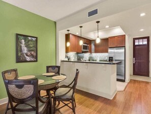 A compact kitchen with wooden cabinets, a central island, and a dining area with wicker chairs.