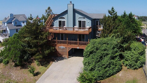 A two-story house with a wooden deck and a covered porch. - My Happy Place: Private Pool & Hot Tub, Rec Room w/ Foosball and Air Hockey (Corolla)