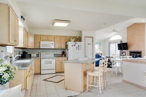 Una cucina moderna con mobili in legno, un'isola centrale e un'area pranzo con sedie bianche.