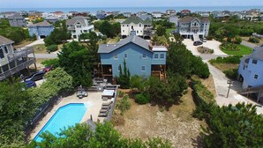 A residential area with a large blue house, a swimming pool, and a view of the ocean. - My Happy Place: Private Pool & Hot Tub, Rec Room w/ Foosball and Air Hockey (Corolla)