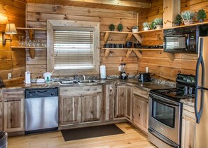 Kitchen features a central island, stove, dishwasher, and microwave, with ample storage and a window for natural light.