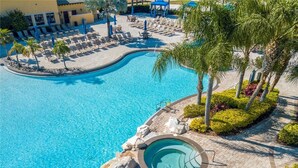 Una piscina grande al aire libre con sillones de descanso y palmeras.
