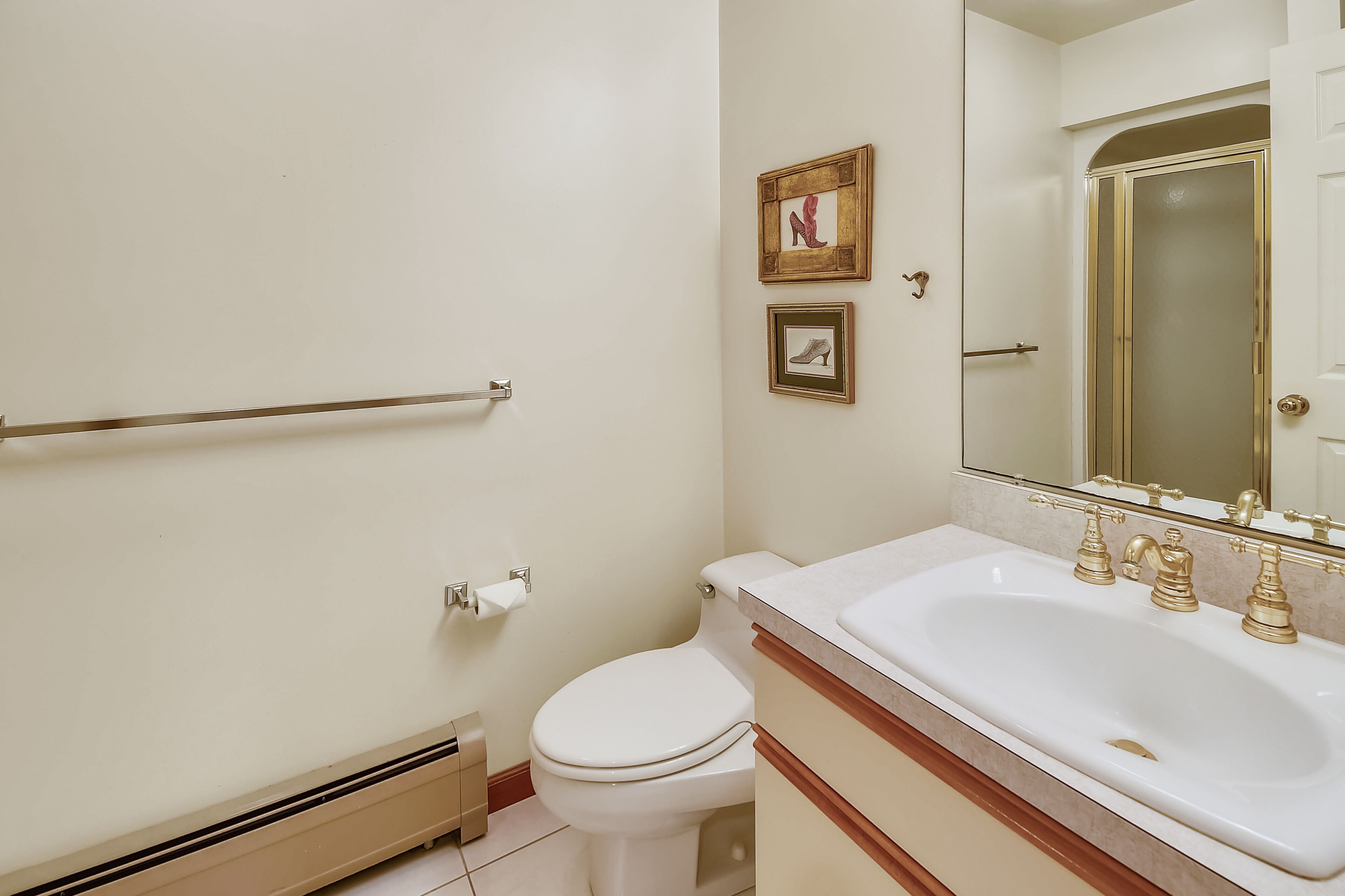Ein Badezimmer mit Toilette, Waschbecken mit goldfarbenen Armaturen und einer Handstange.