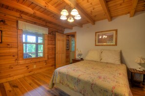 A wooden cabin bedroom with a bed, a window, a door, and a ceiling light fixture. - 2BR cabin in Bryson City with hot tub, fireplace, WiFi, and mountain views. Free train and rafting (Bryson City)