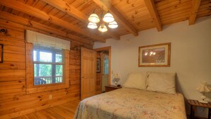 Ein Schlafzimmer einer Holzhütte mit einem Bett, einem Fenster und einer Tür.