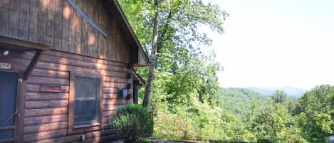 A wooden cabin with a large window, a door, and a sign that reads 'Welcome.'