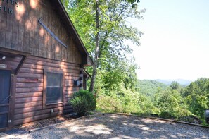 Une cabane en bois avec une grande fenêtre, une porte et une pancarte sur laquelle on peut lire « Bienvenue ».