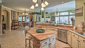A spacious kitchen with a large island, a dining area with a chandelier, and a view of the outdoors. - Luxurious Home w/ Private Pool & Lanai Near Tampa! (Tampa)